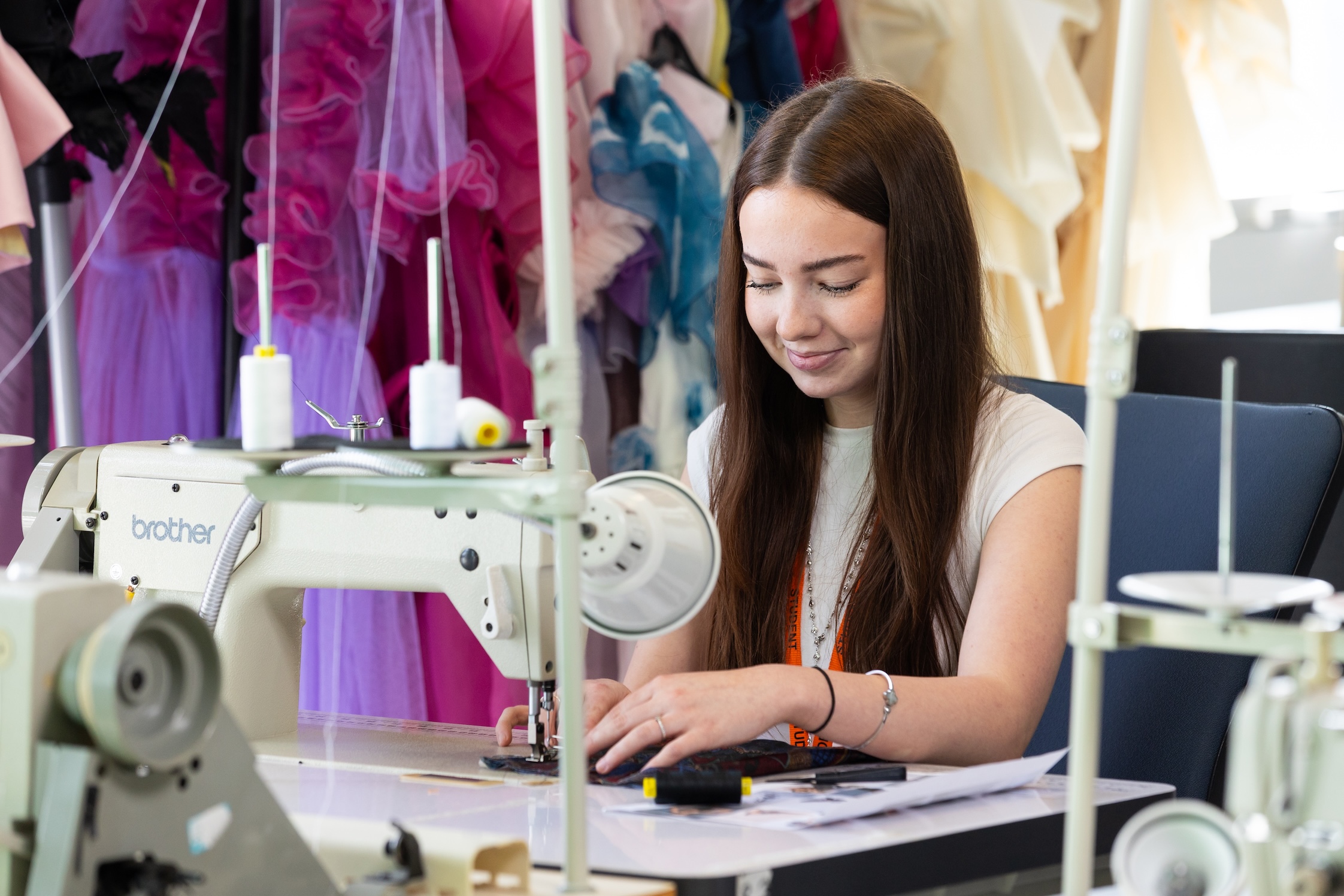 Student sits in front of sewing machine 