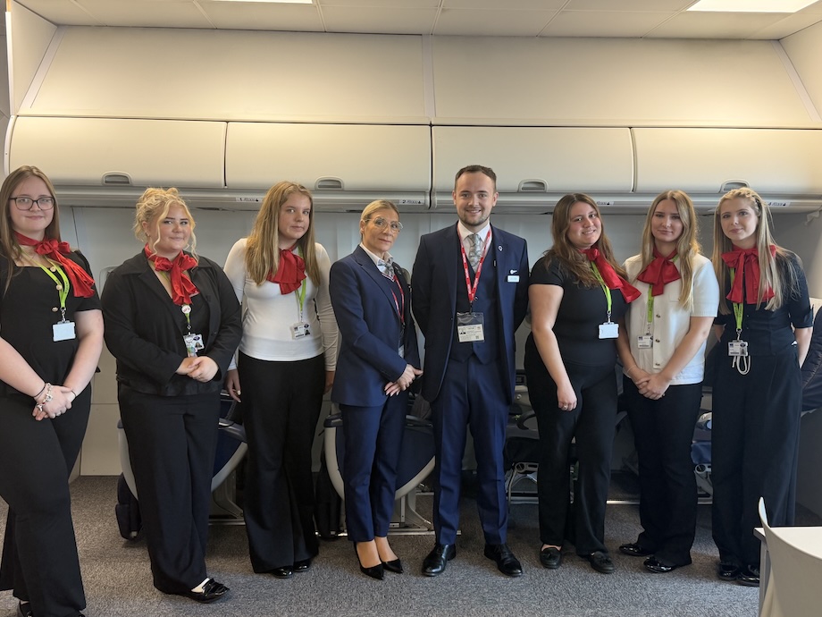 Two British Airways cabin crew stand in the centre of a group, surrounded by six college Travel and Tourism students